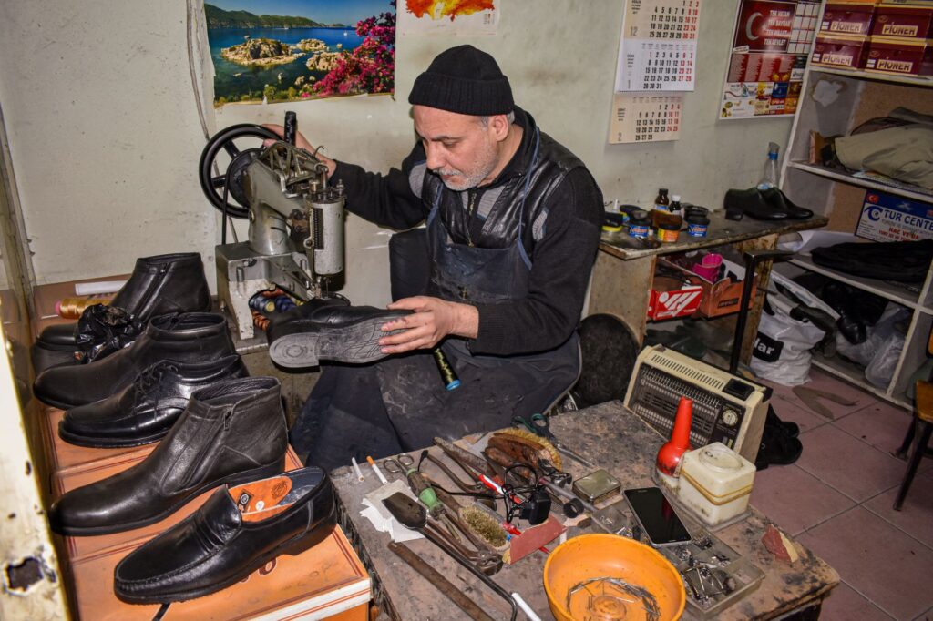 Cordonnier réparant des chaussures en cuir à la machine dans son atelier