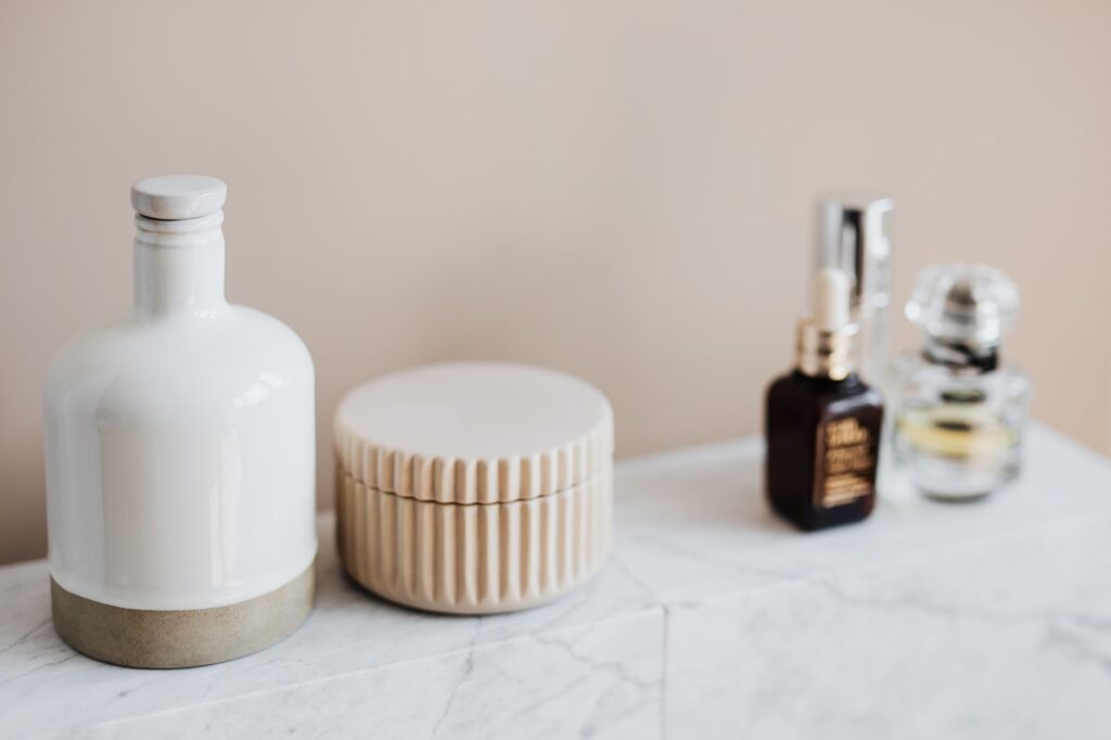 Flacons et pots cosmétiques rechargeables alignés sur une étagère de salle de bain