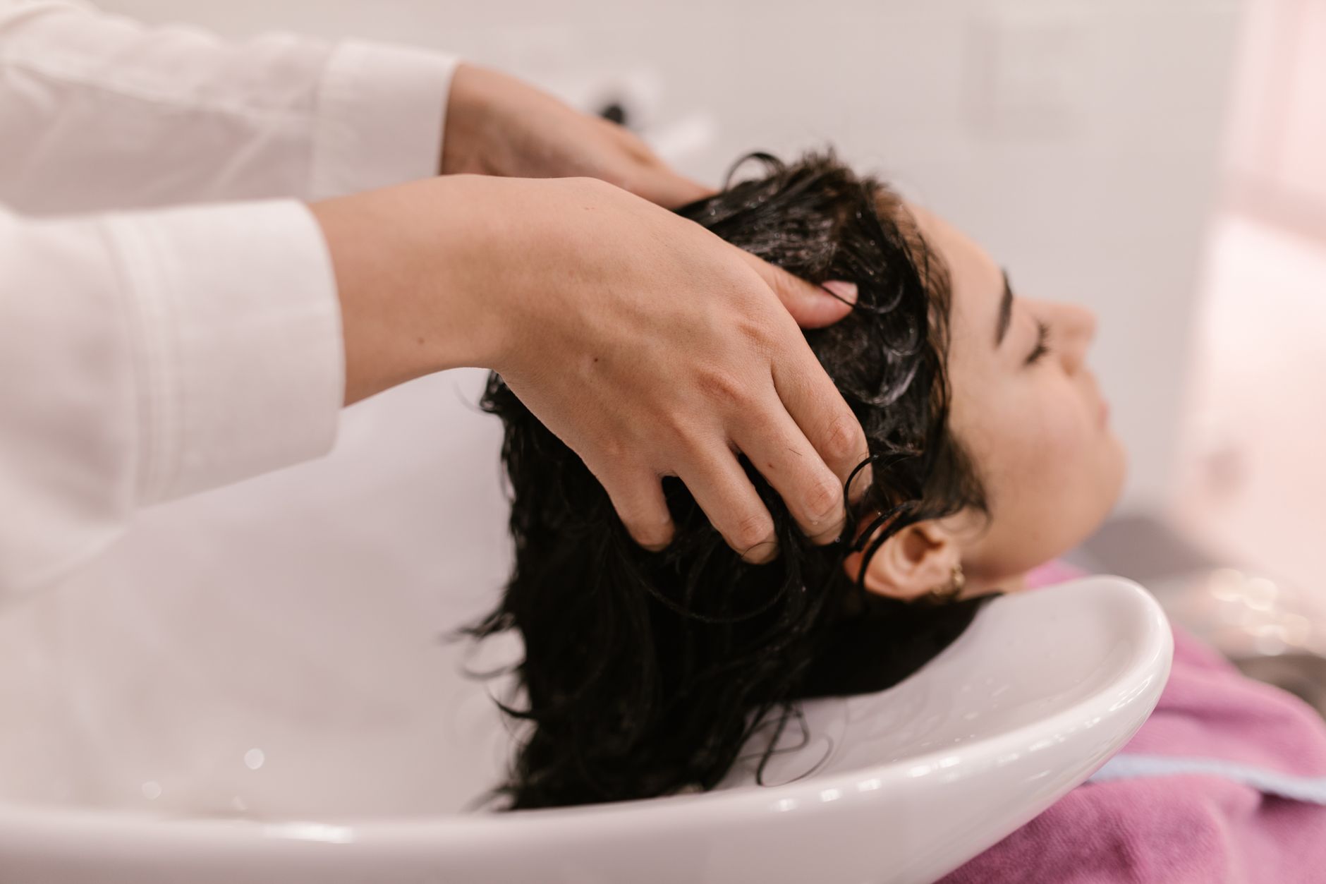 Cliente allongée au bac de lavage pendant un soin capillaire en salon