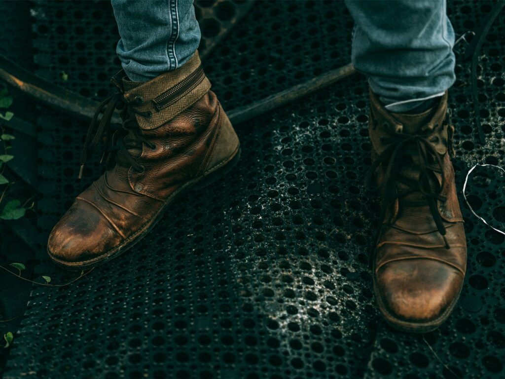 Bottines en cuir patinées posées sur un sol métallique ajouré