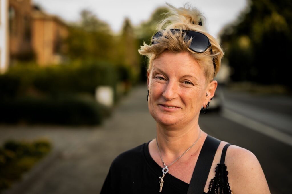 Portrait souriant d'une femme aux cheveux blonds courts, lunettes relevées