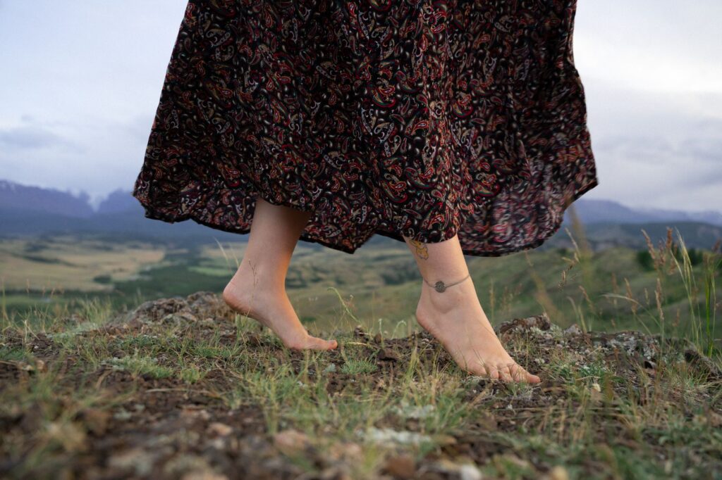 Bas d'une jupe longue imprimée en mouvement, pieds nus dans l'herbe