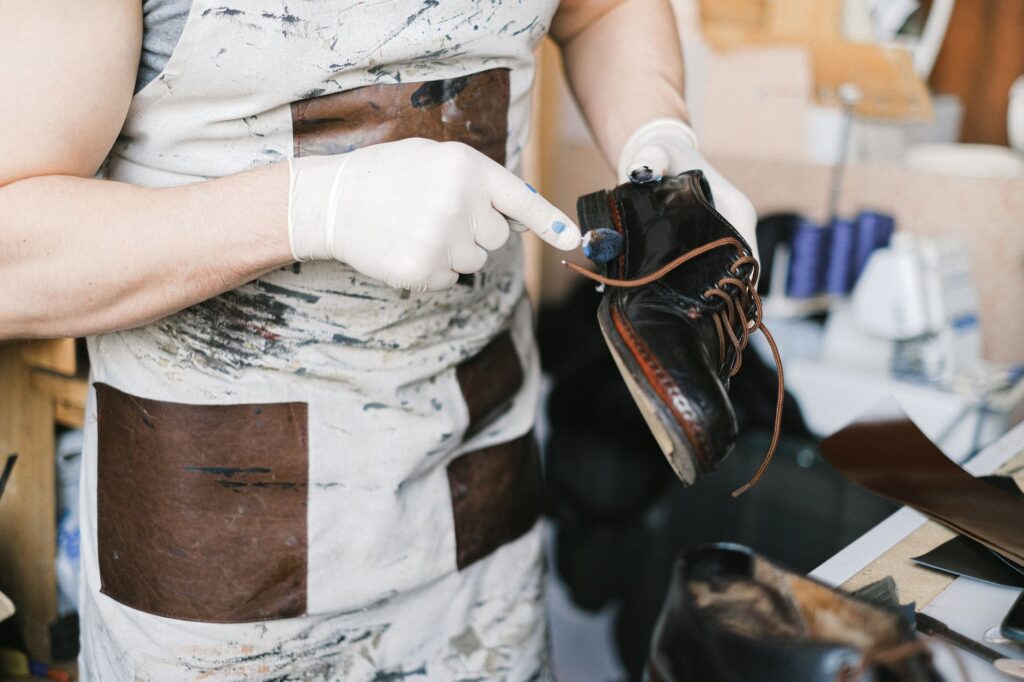 Artisan ganté lustrant une chaussure en cuir dans un atelier