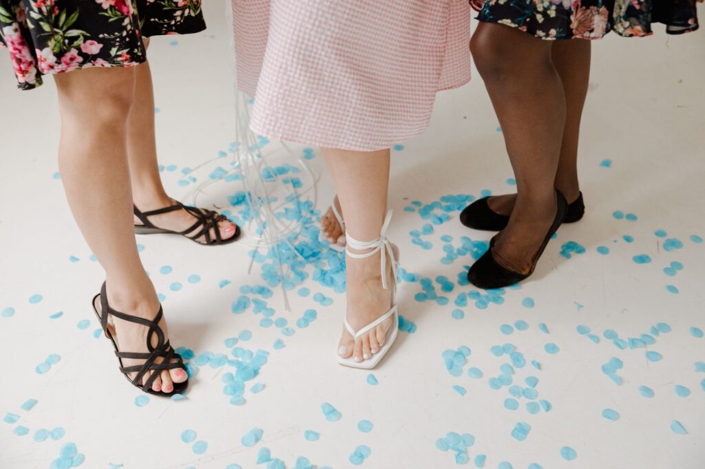 Trois paires de jambes en sandales plates à brides, confettis bleus au sol